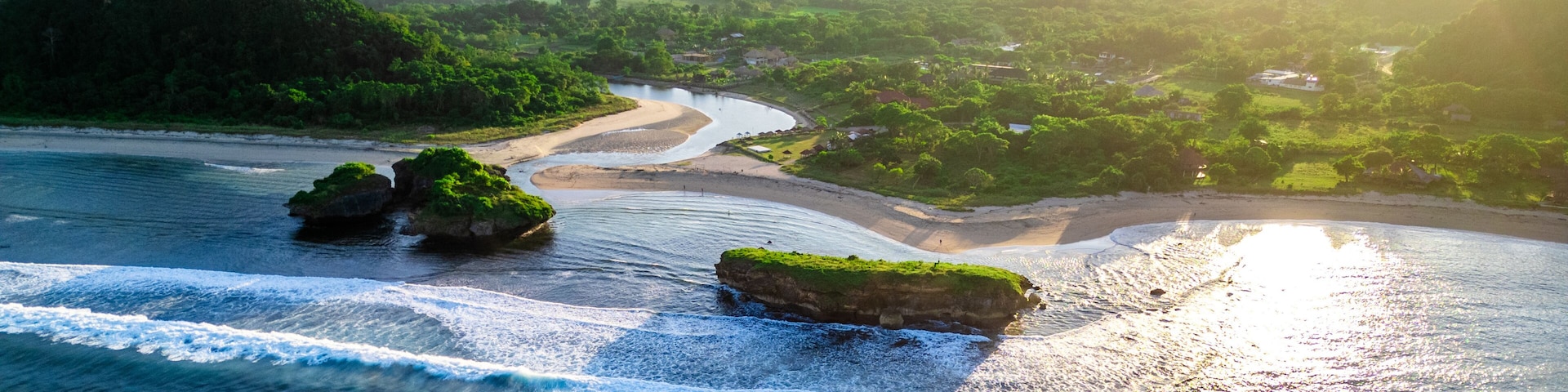 Un paisaje costero con un río, colinas verdes y afloramientos rocosos.