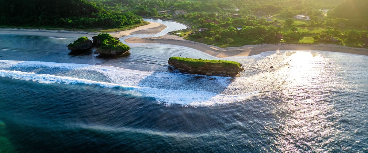 A coastal landscape with a river, green hills, and rocky outcrops.