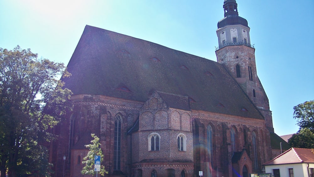 Une grande église en briques, dotée d’un imposant clocher et de fenêtres en arc de cercle.