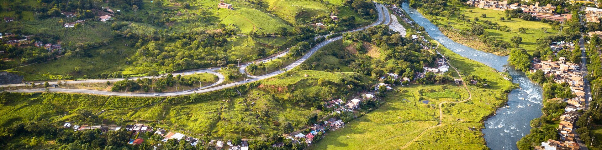 Un río sinuoso atraviesa un valle exuberante con casas dispersas y un pequeño pueblo.