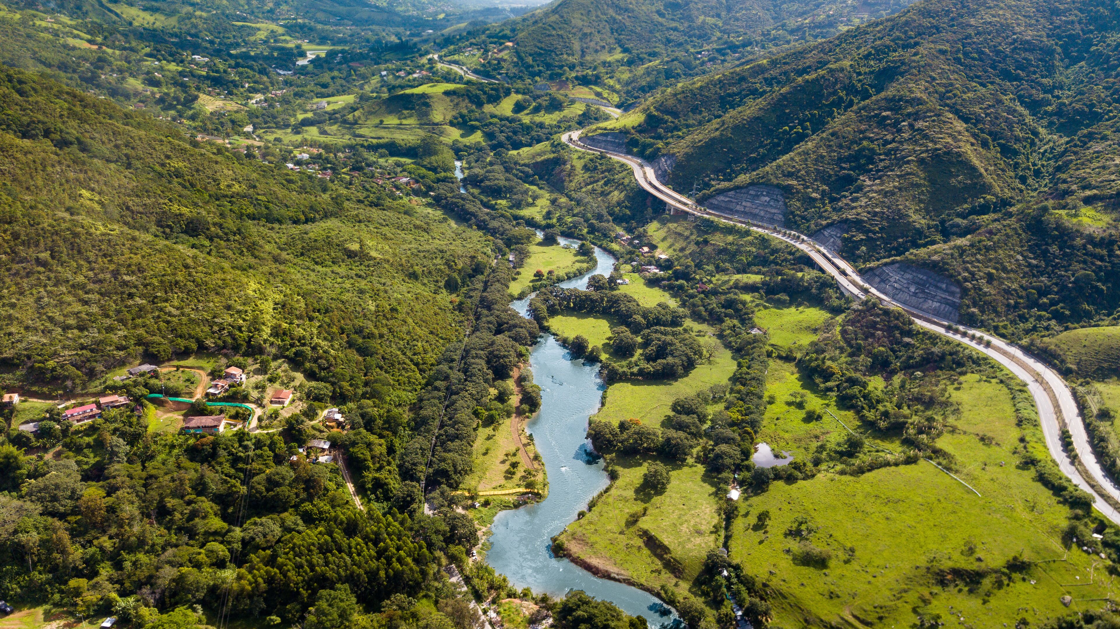 A winding river through a lush valley with a road curving along the river.