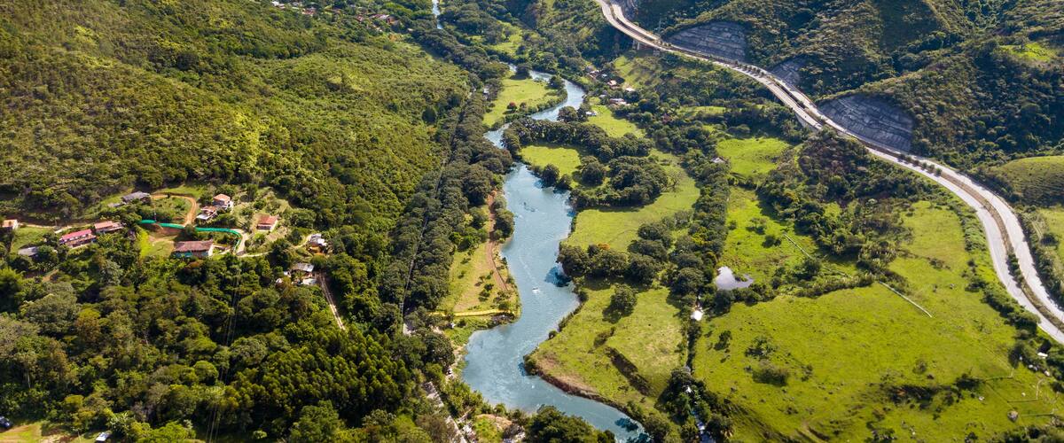 A winding river through a lush valley with a road curving along the river.
