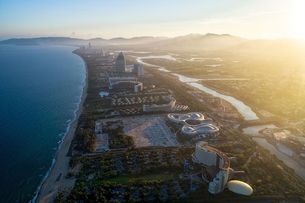 An aerial view of a coastal city with a prominent hotel, a river, and a beach.