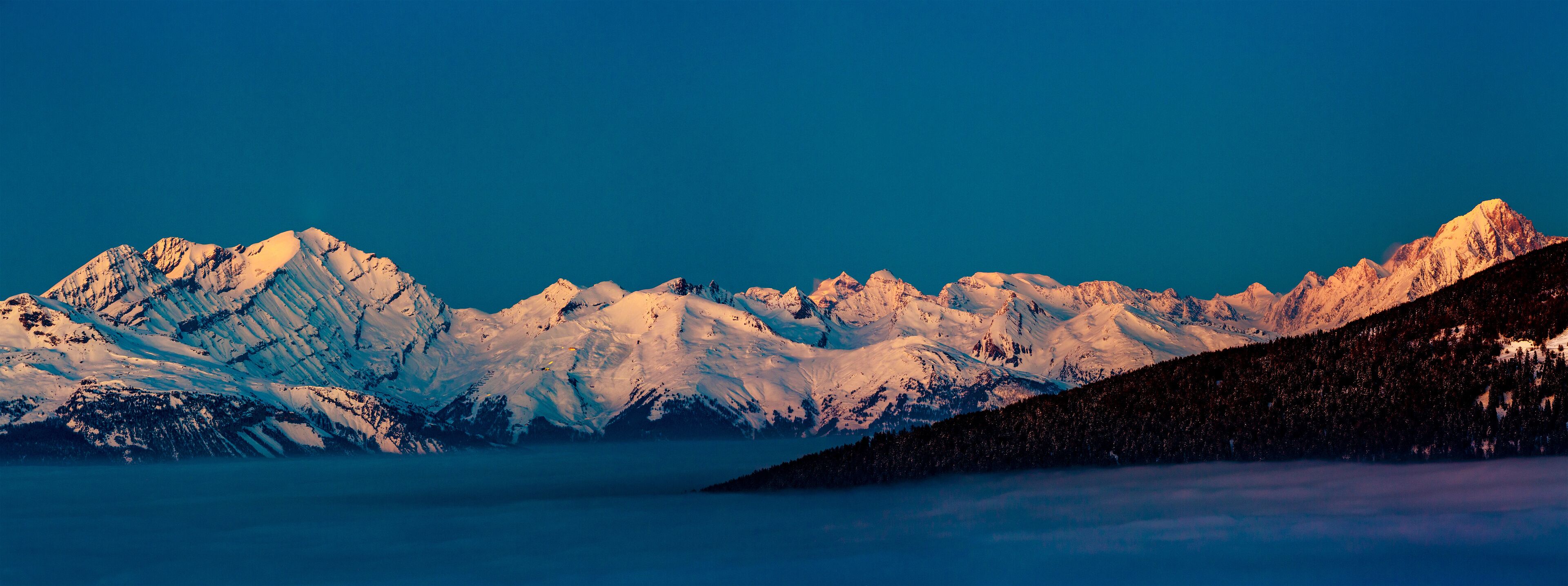 Snow-covered mountain peaks under a clear blue sky.