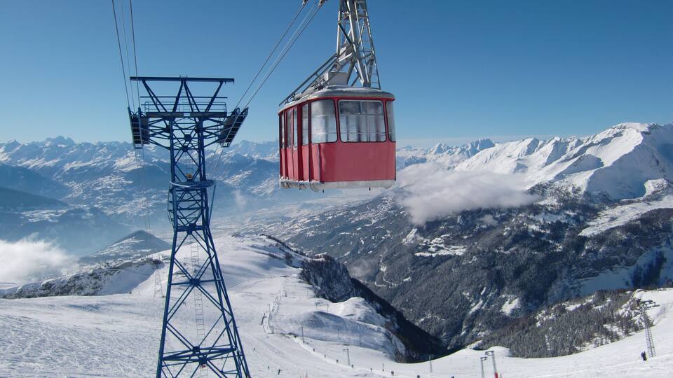 A cable car system in a snowy mountainous area with clear skies.