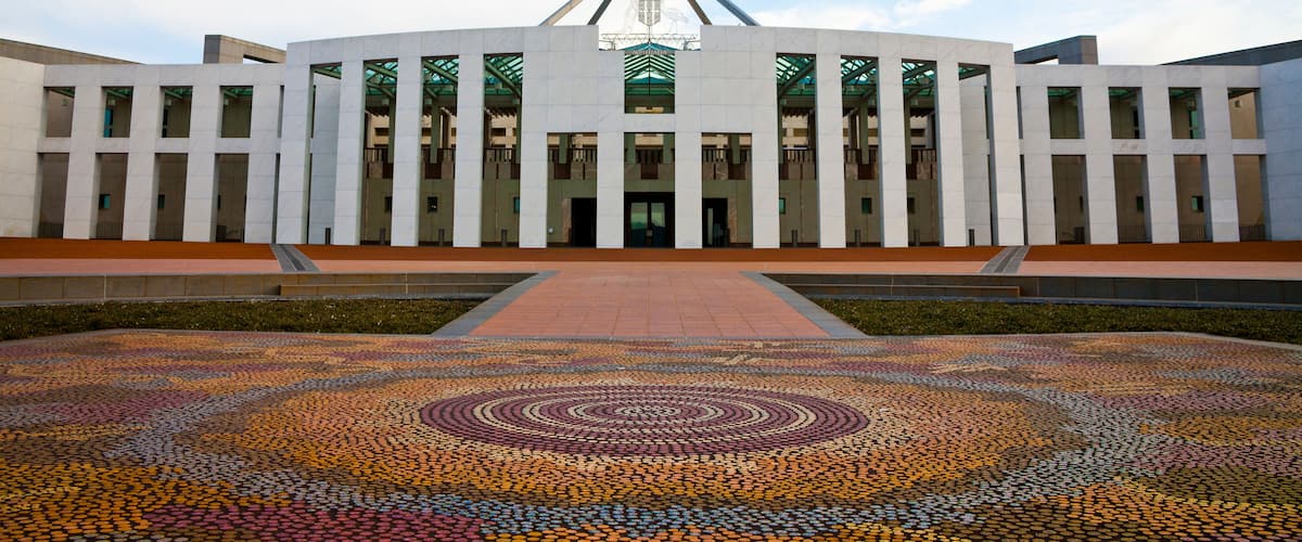 A modern building with a flagpole, a patterned pavement, and a clear sky.