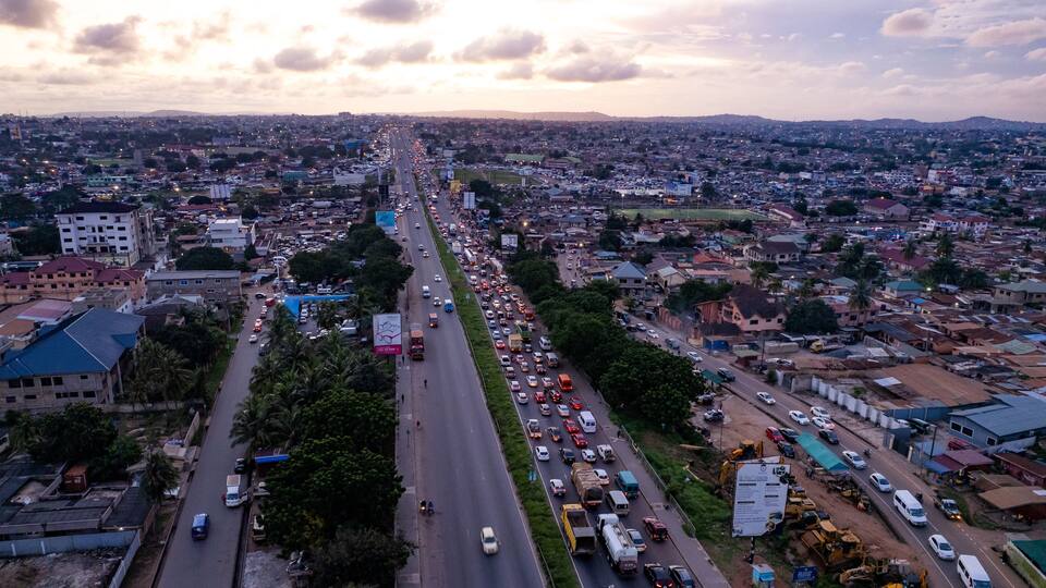 A busy urban street with heavy traffic, buildings, and construction sites.