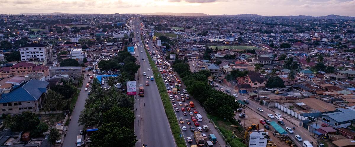 A busy urban street with heavy traffic, buildings, and construction sites.