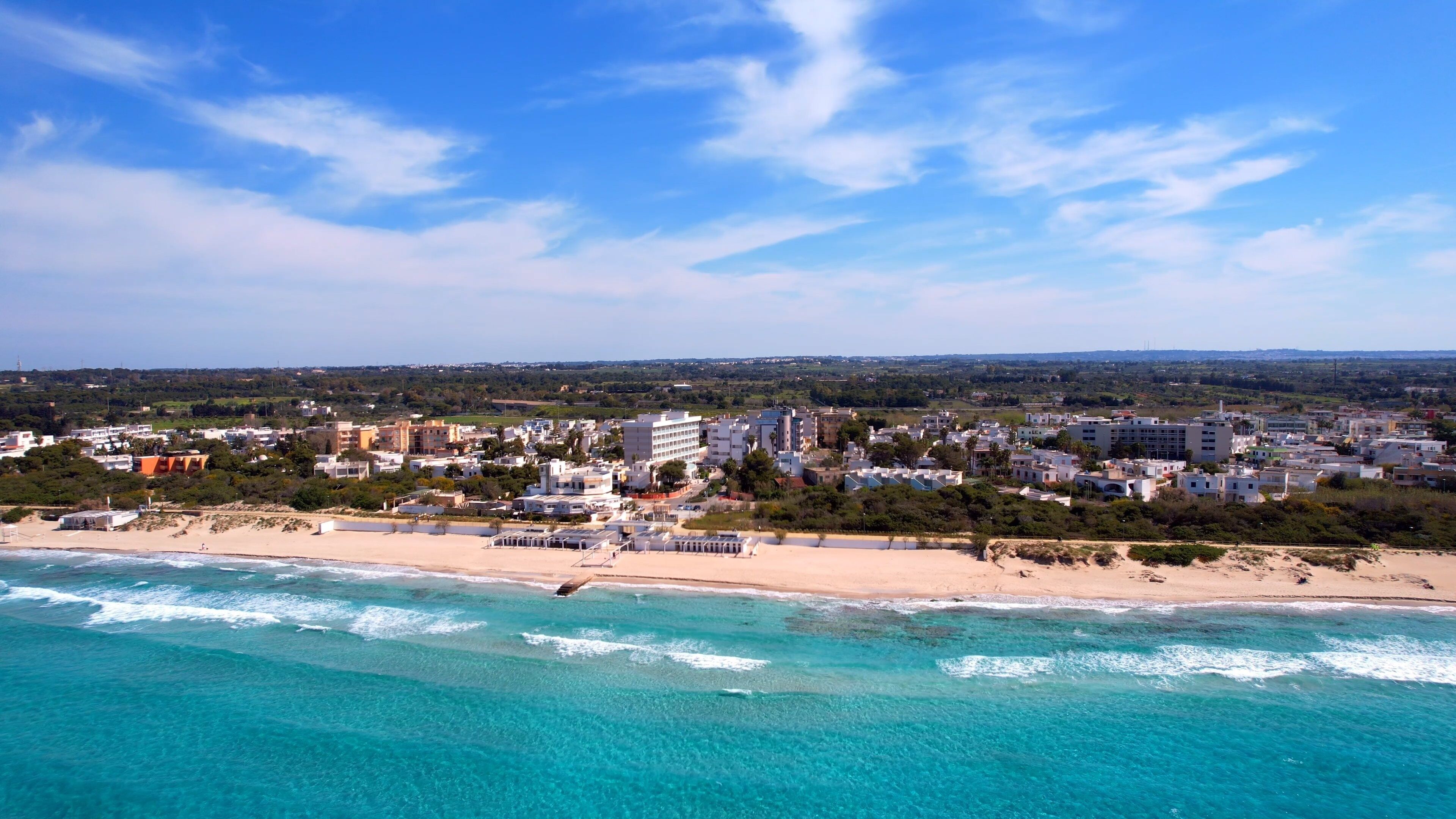 A coastal cityscape with a beach and clear turquoise waters.