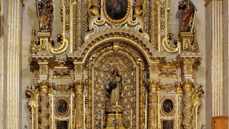 Un altar religioso ornamentado con detalles dorados y estatuas.