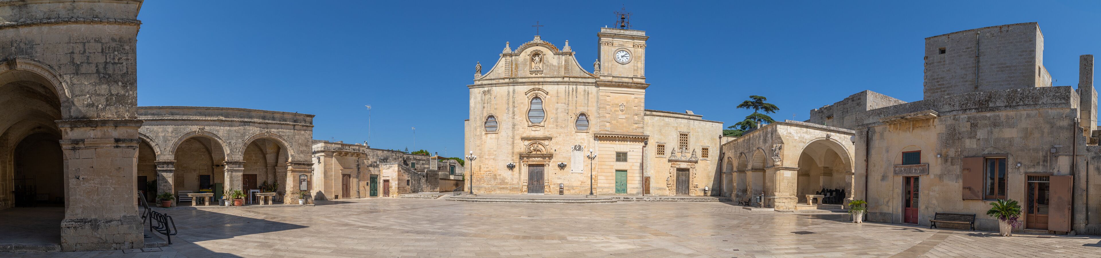 A historic square with a prominent church featuring a bell tower and arches.
