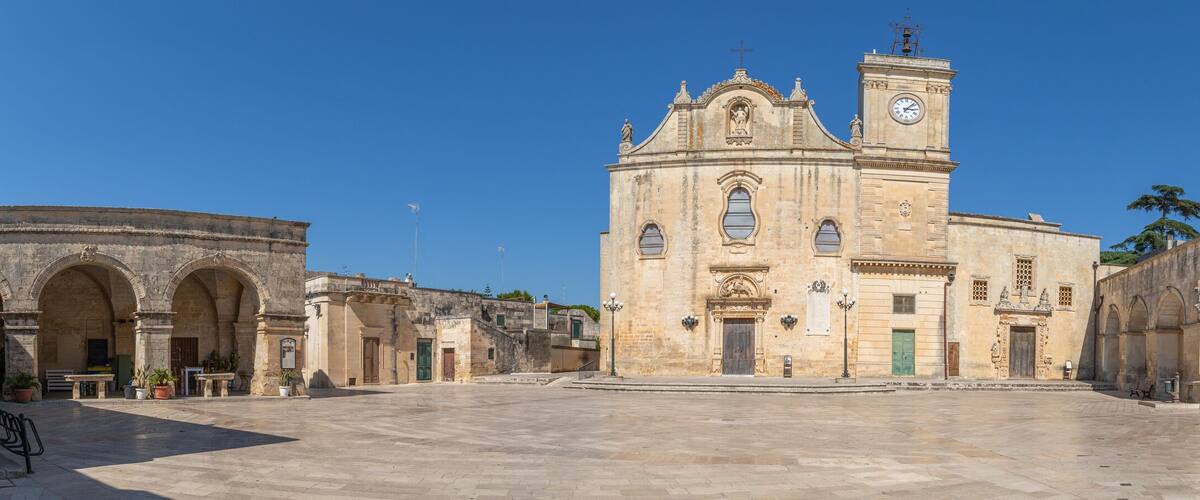 A historic square with a prominent church featuring a bell tower and arches.