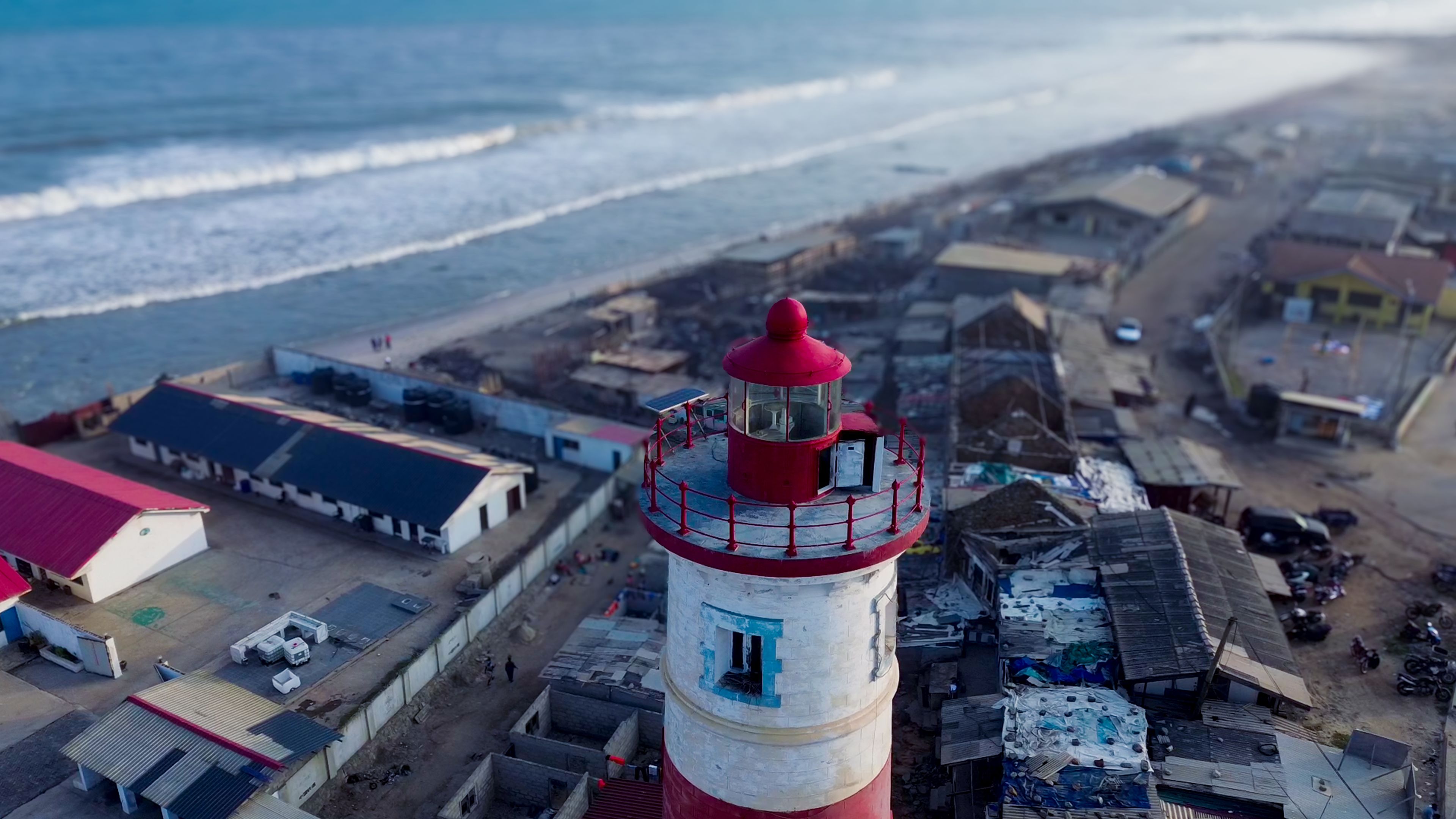 Aerial view of Jamestown Lighthouse with its distinctive red and white tower, surrounded by coastal buildings and the Atlantic Ocean in Accra, Greater Accra Region, Ghana.