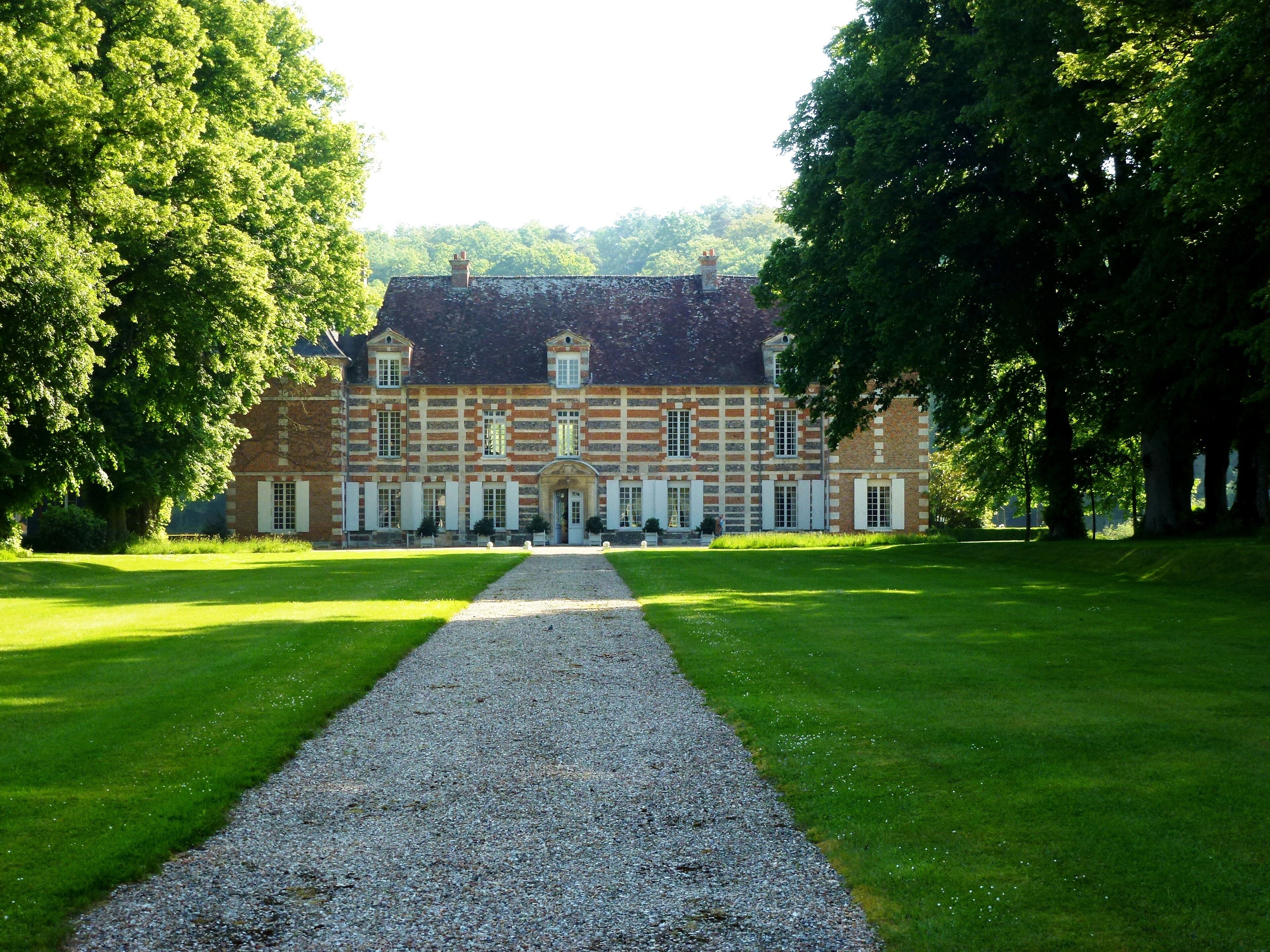 A large, historic building with a symmetrical facade, surrounded by lush green lawns and trees.