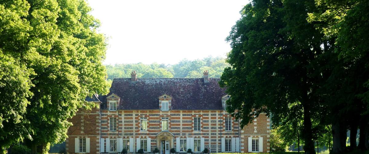 A large, historic building with a symmetrical facade, surrounded by lush green lawns and trees.