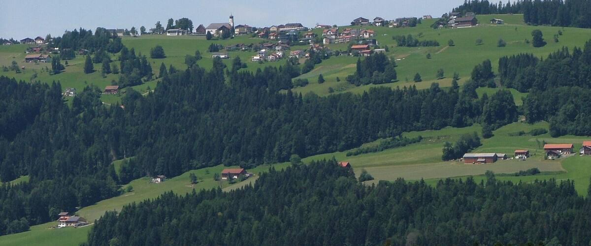 A mountainous landscape with scattered houses and a church on a hill.