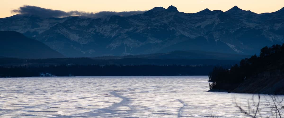A frozen lake with mountains in the background.