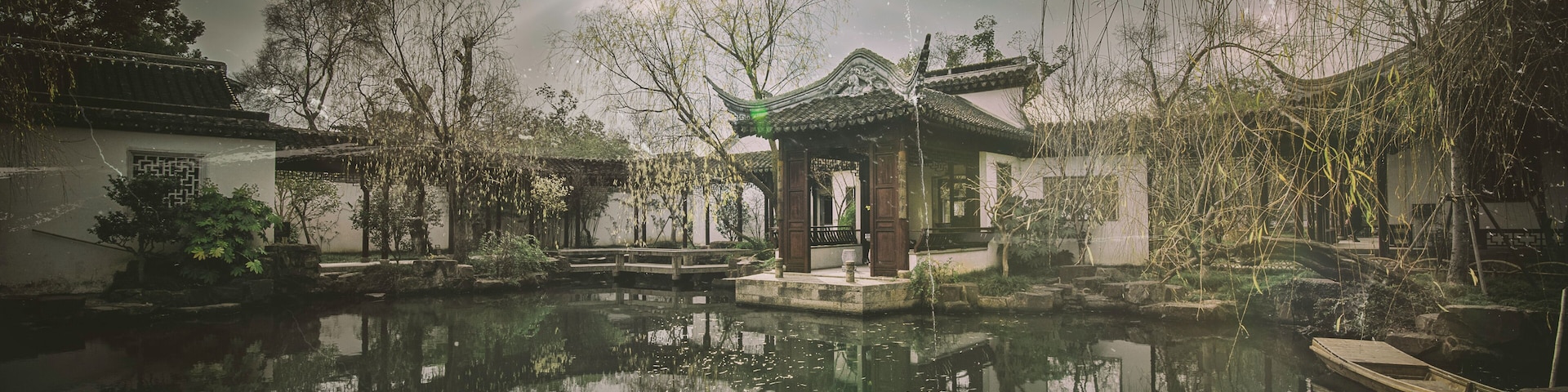 Um pátio chinês tradicional com um lago, refletindo a arquitetura e as árvores ao redor.