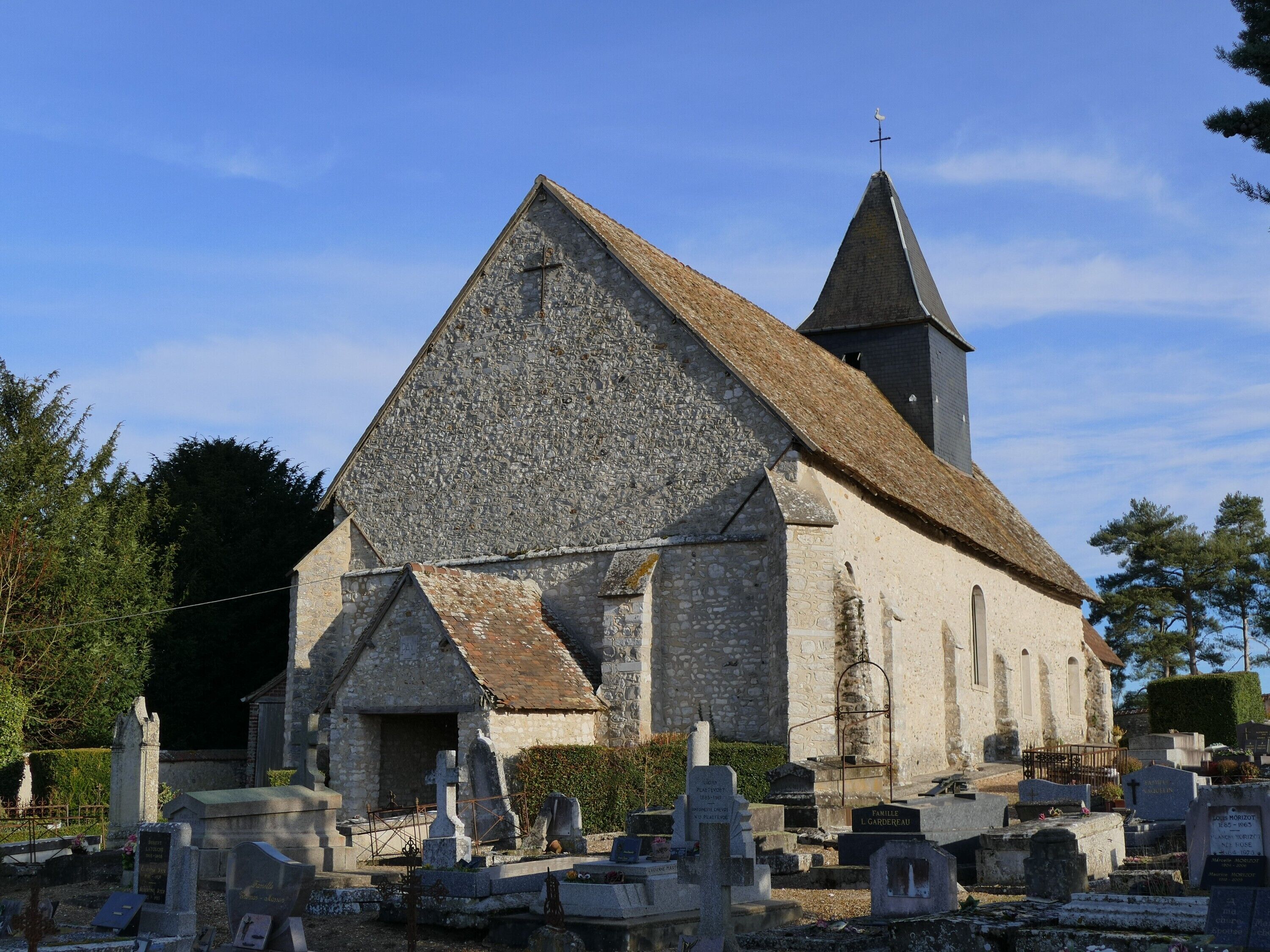 A stone church with a steep roof and a bell tower.