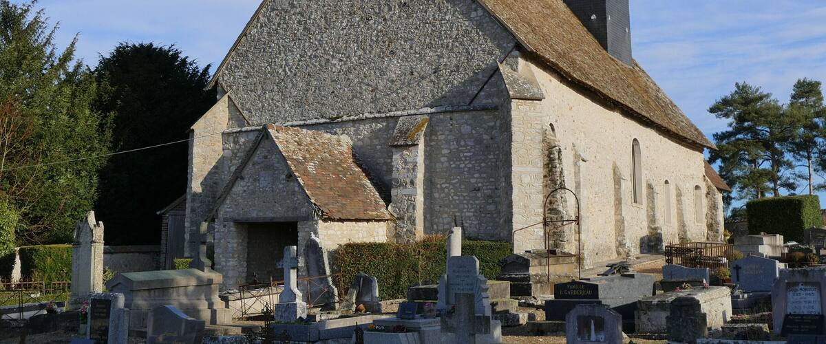 A stone church with a steep roof and a bell tower.