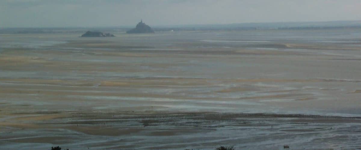 A beach with a distant island and a clear sky.