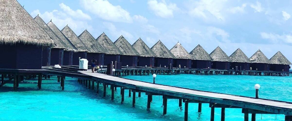A series of overwater bungalows connected by a wooden pier over turquoise waters.