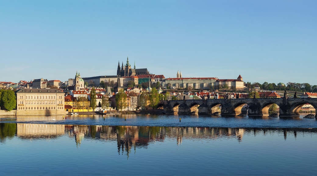 A river with a stone bridge, historic buildings, and a prominent church with a green spire.