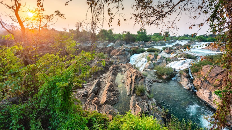 A river flowing through a rocky landscape with dense foliage and trees.