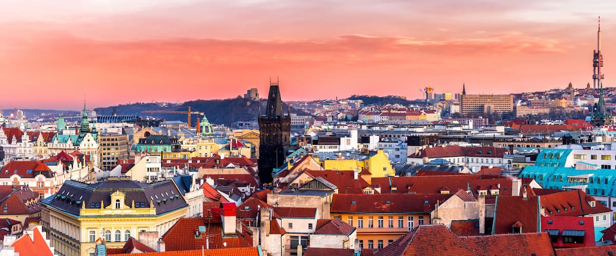 Ein weiter Panoramablick auf eine Stadtlandschaft mit einem markanten Kirchturm, bunten Gebäuden und einem hohen Sendeturm.