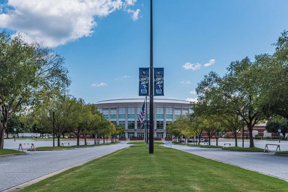 A stadium with a large American flag and banners reading "Welcome to the Lion's Den."