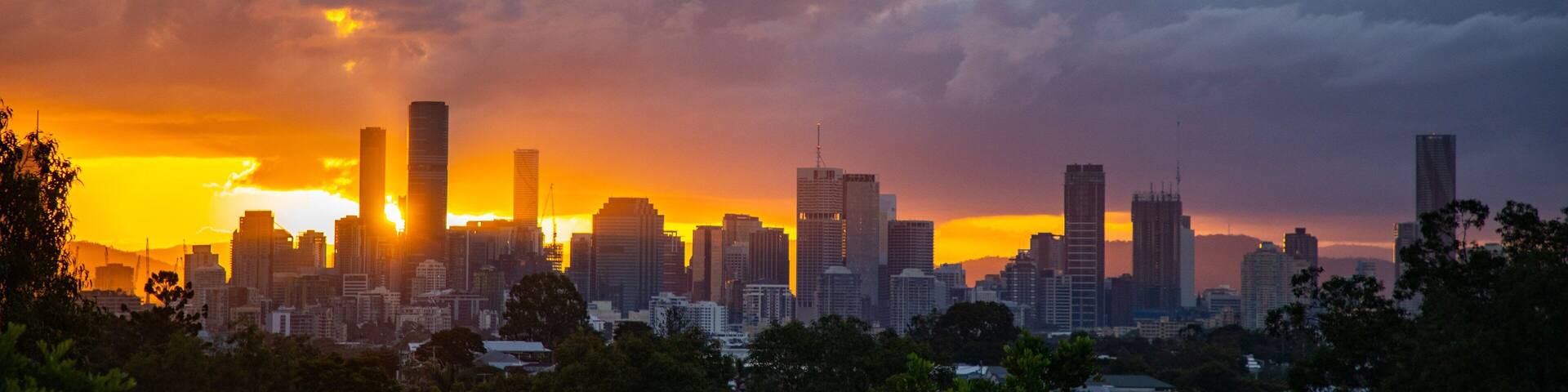 A city skyline at sunset with tall buildings silhouetted against a vibrant sky.