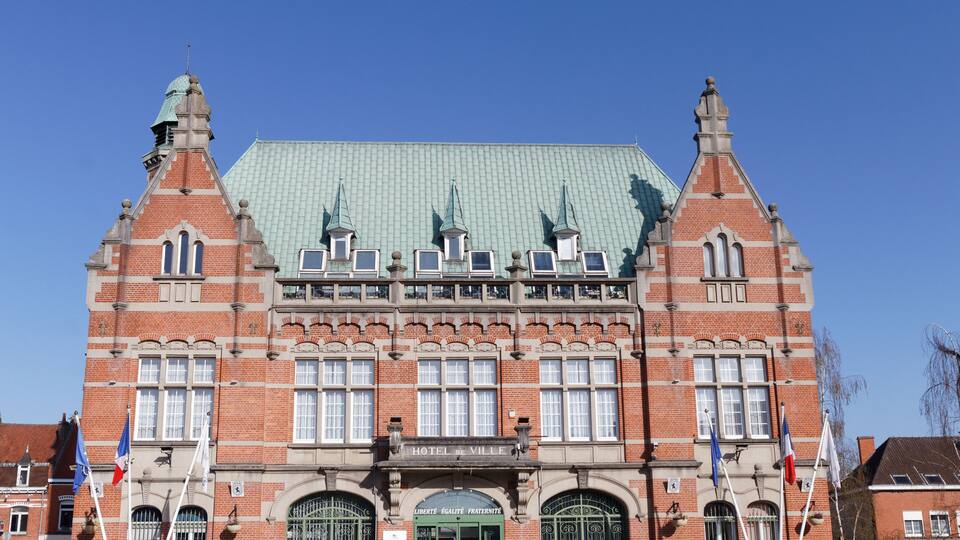 A historic building with a green roof, red brick facade, and multiple spires.