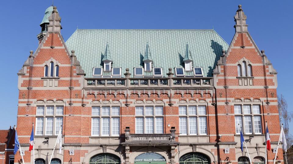 A historic building with a green roof, multiple windows, and flags.