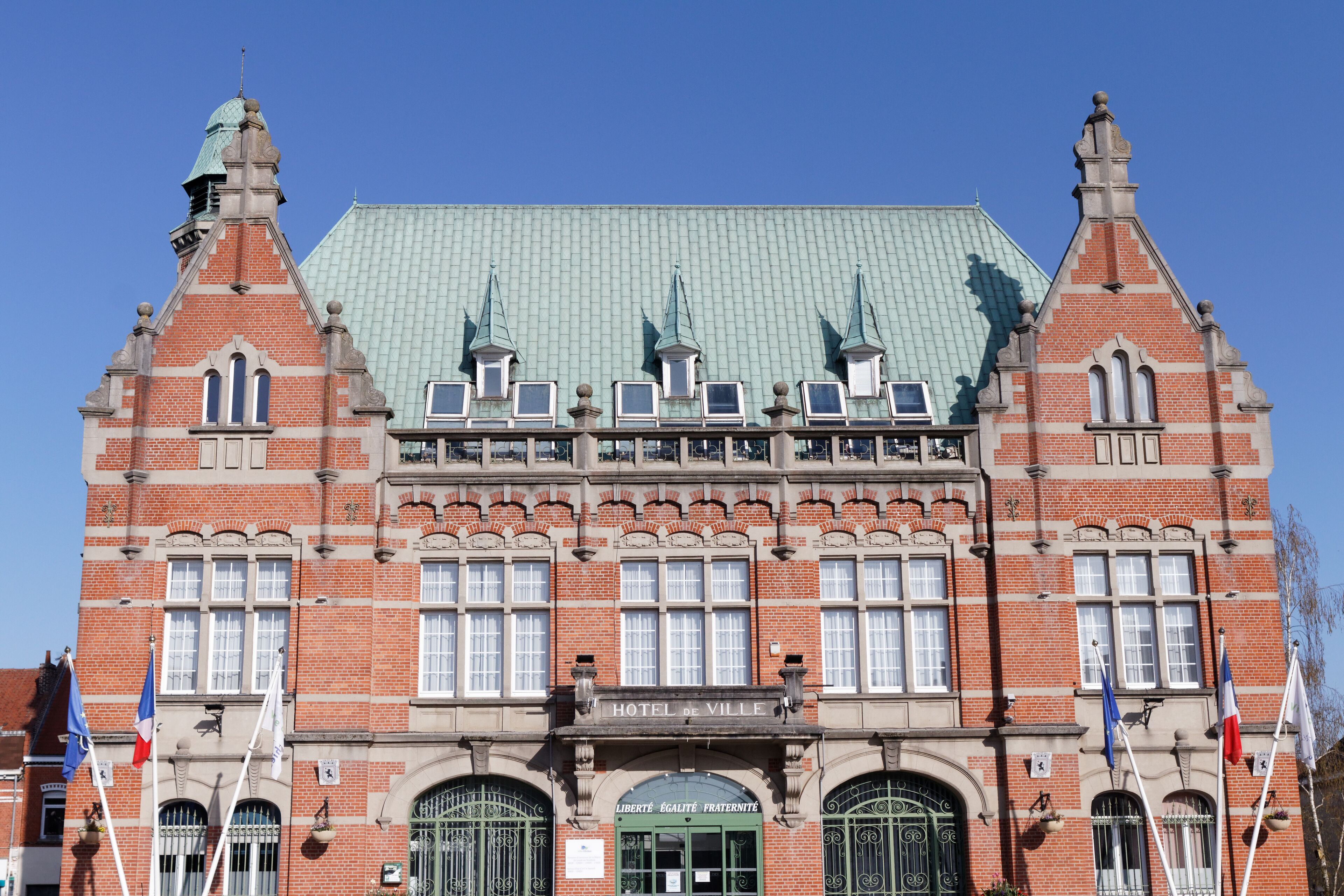 A historic building with a green roof, multiple windows, and flags.