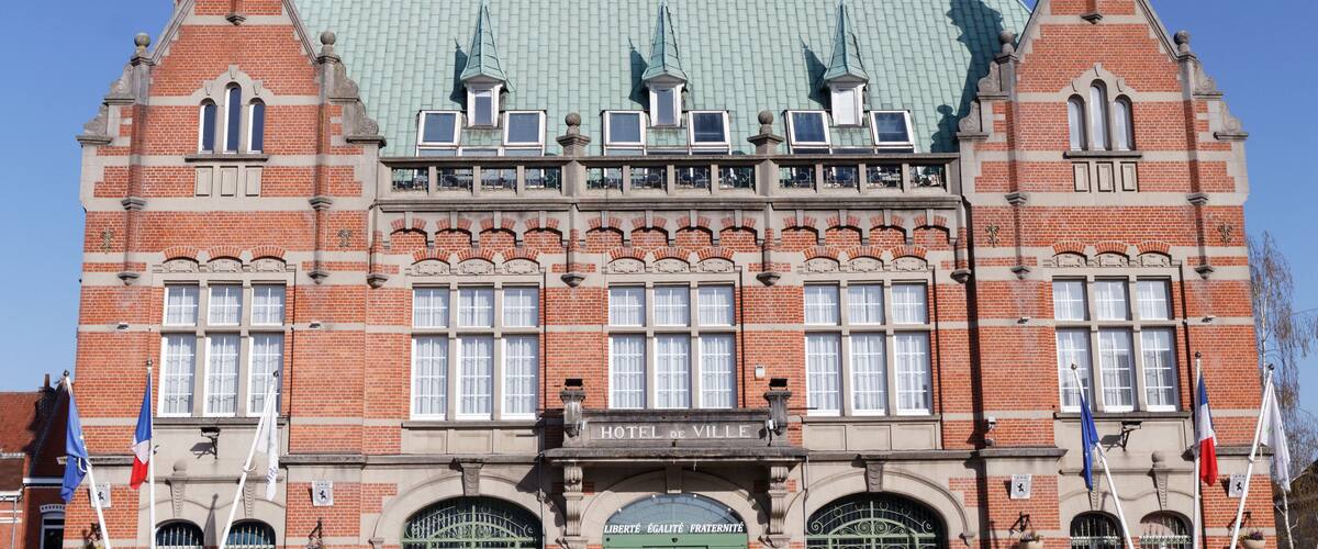 A historic building with a green roof, multiple windows, and flags.