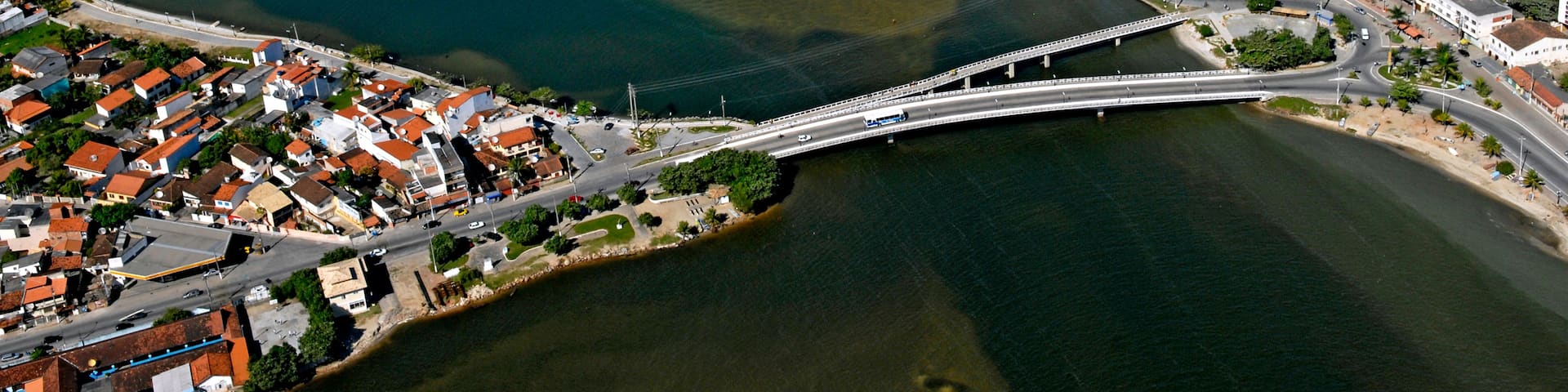 An aerial view of a coastal town with a prominent white church, a bridge, and a mix of residential and commercial buildings.