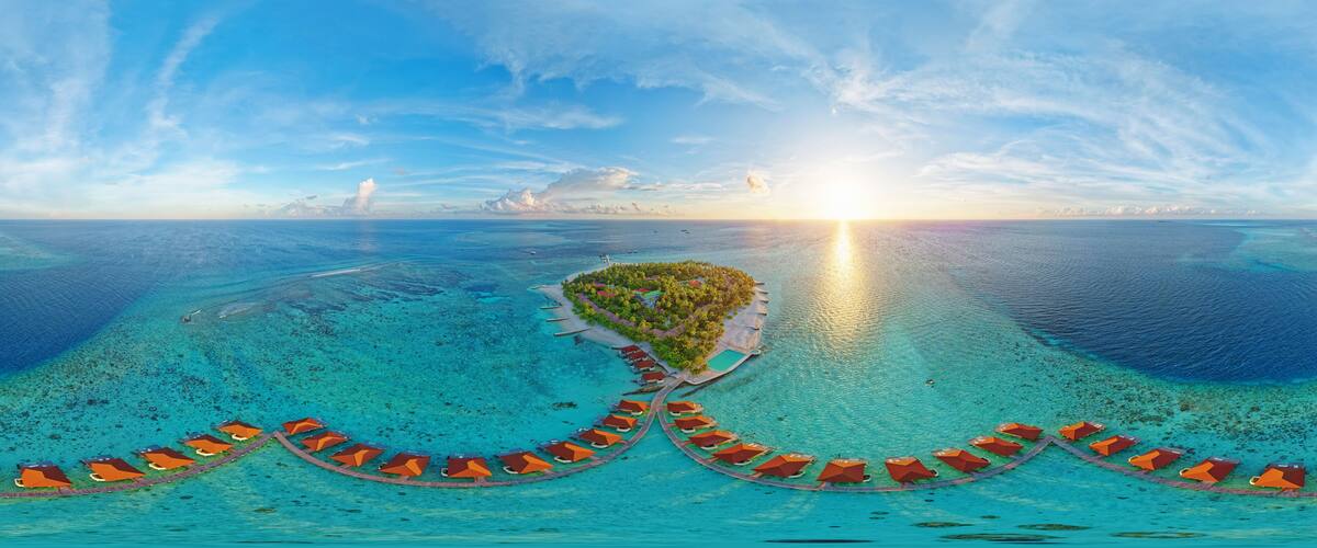 An aerial view of a tropical island with a crescent-shaped resort and clear turquoise waters.