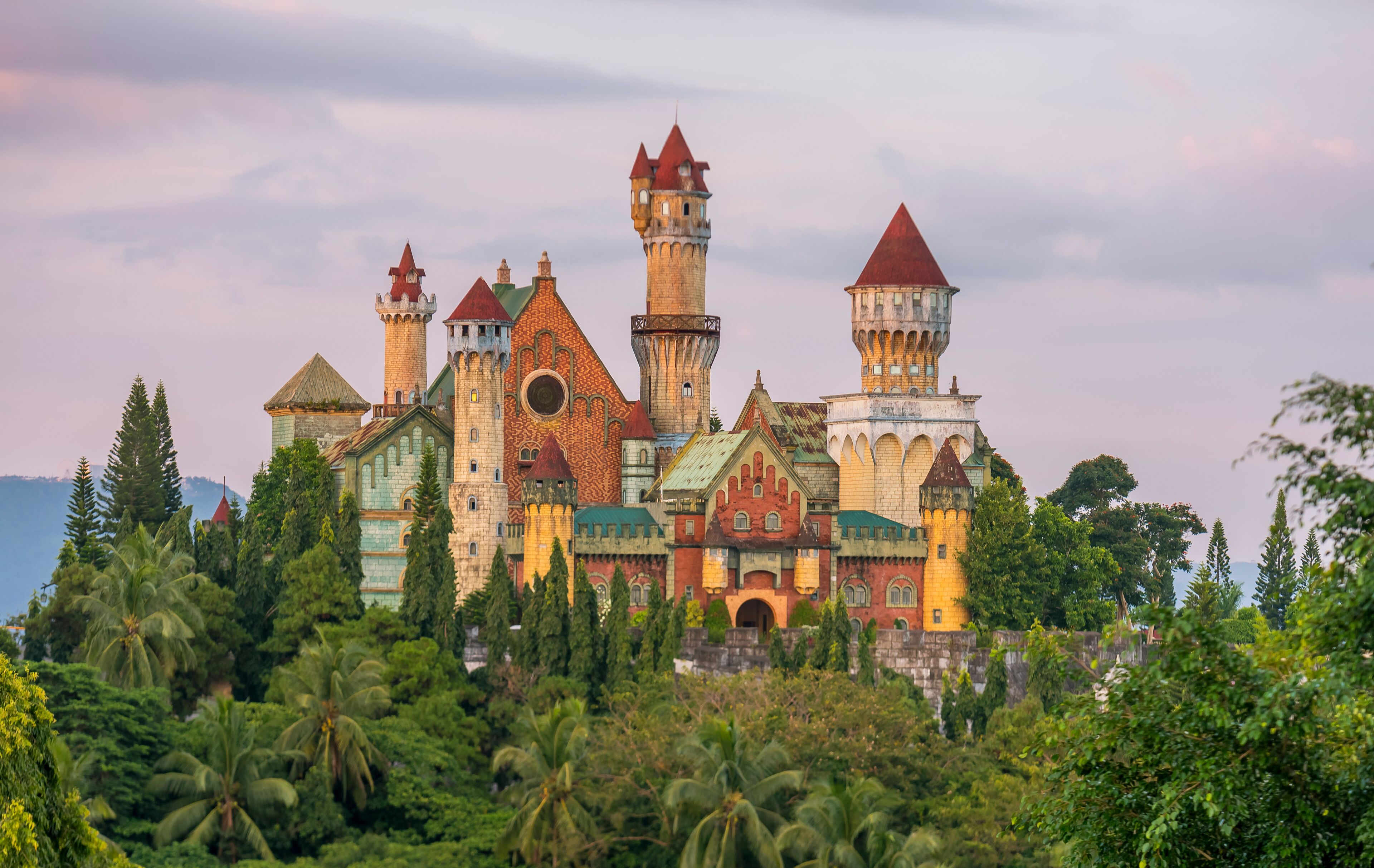 A castle with multiple towers and turrets surrounded by lush greenery.