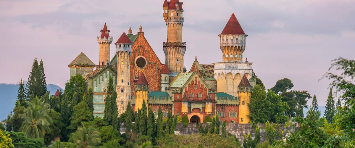 A castle with multiple towers and turrets surrounded by lush greenery.