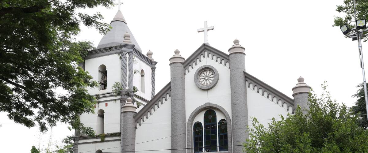A church with a cross on top, a clock, and a sign that reads "Porta Sancta".