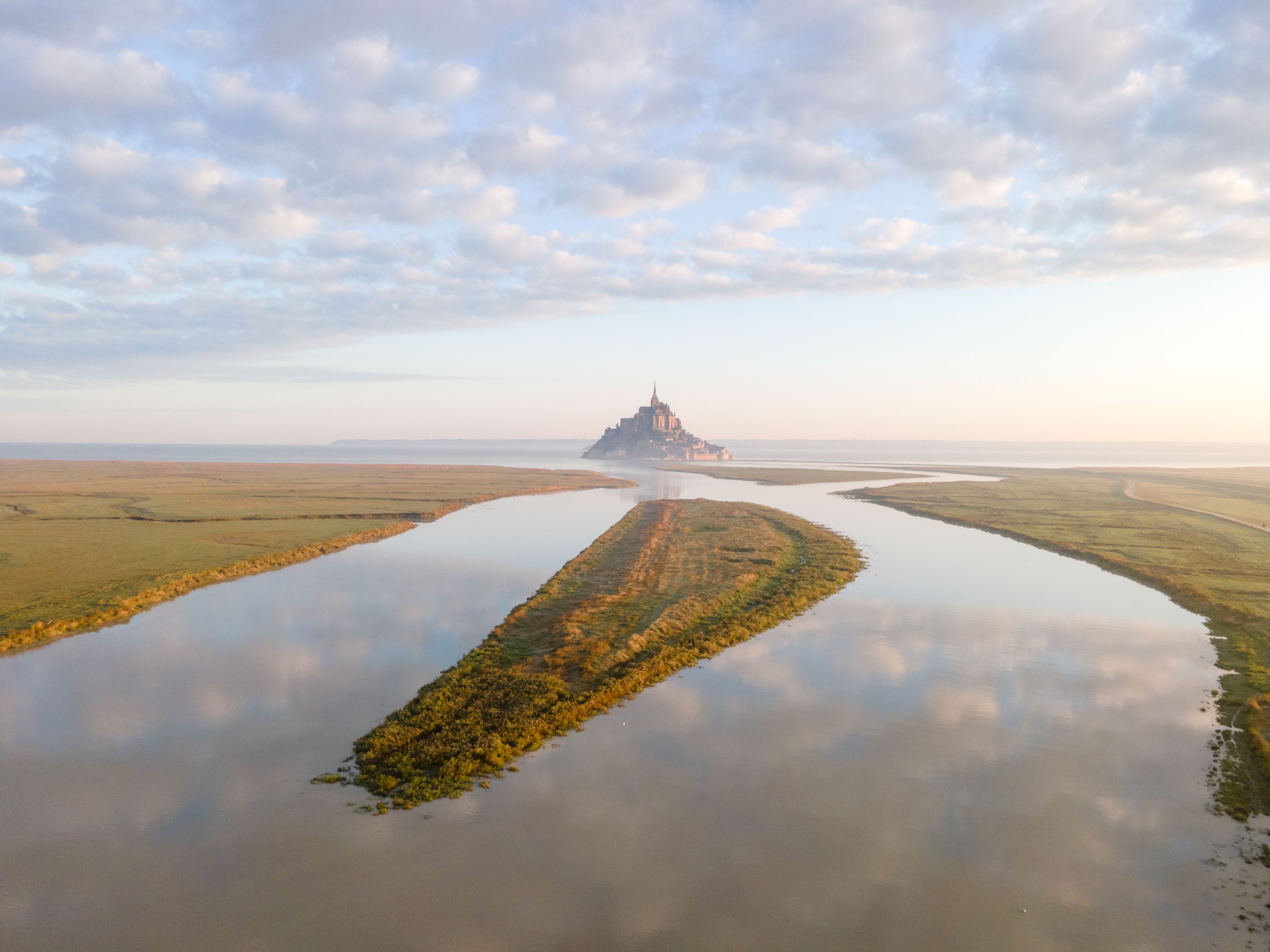 Un château situé sur une île fluviale, entouré d’eau.