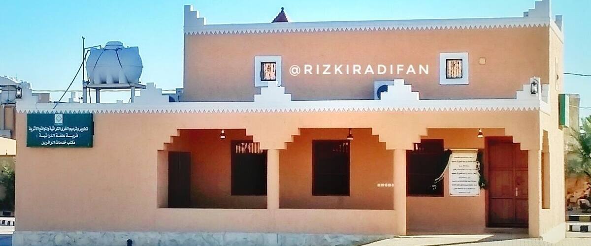 A building with a sign reading "@RIZKIRADIFAN" and a signboard with text in a foreign language.