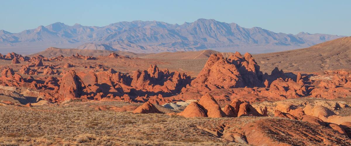 A desert landscape with red rock formations and distant mountains.