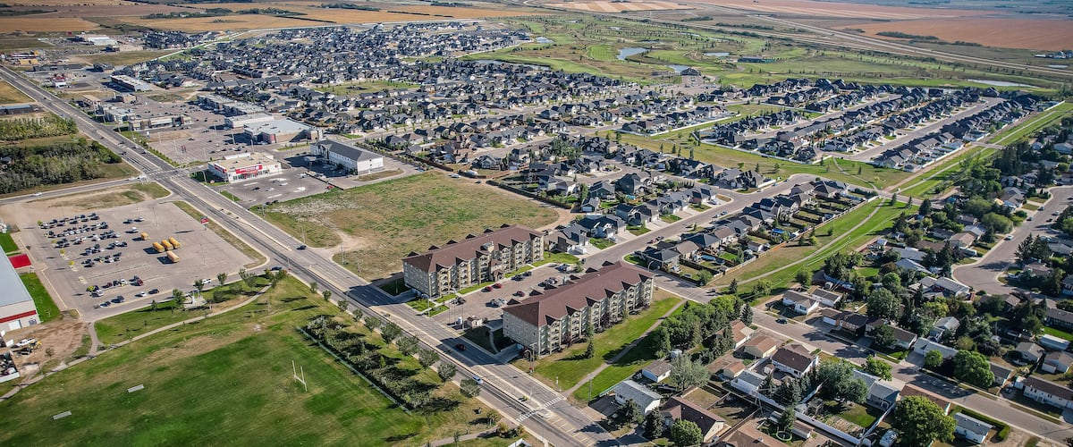An aerial view of a residential area with houses, roads, and a large industrial building.