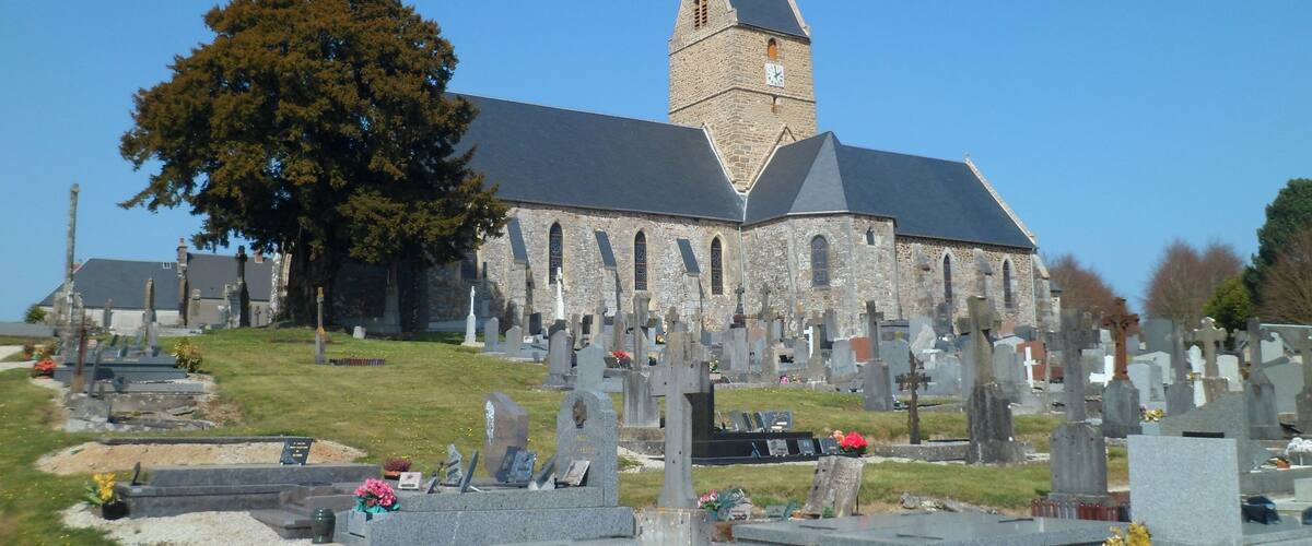 A church with a tall tower and a cemetery in front.