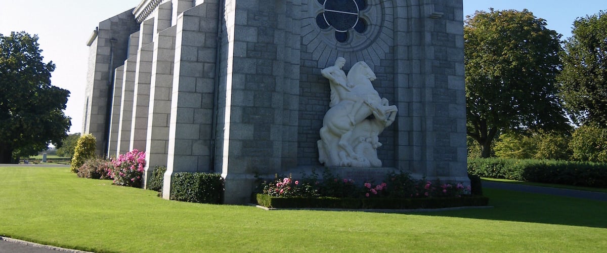 A large stone building with a tall tower and a statue of a man on a horse.