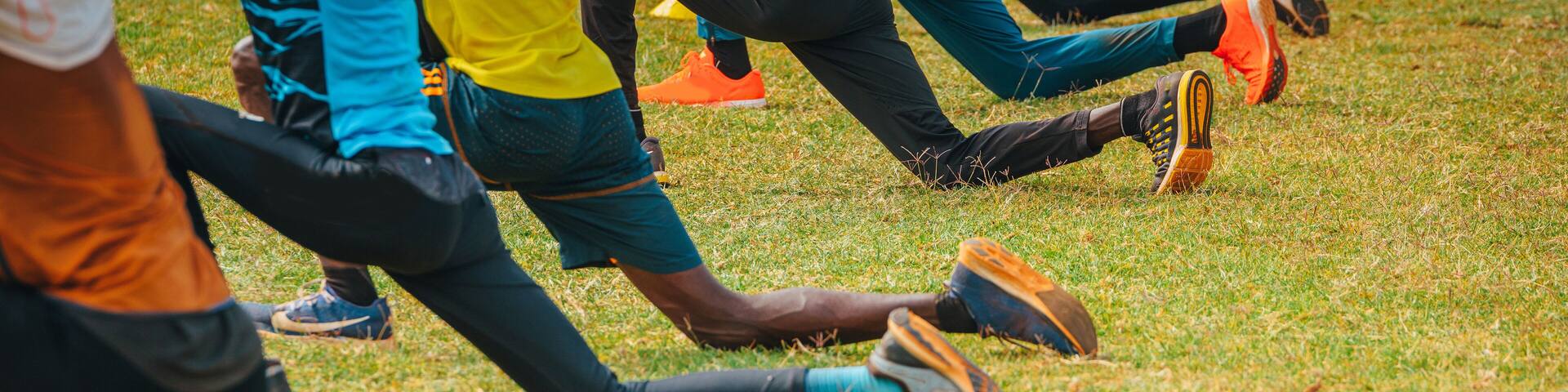Stretching and warm-up of African runners. Joggers and marathon runners prepare to run on green grass. Photo from training in Kenya