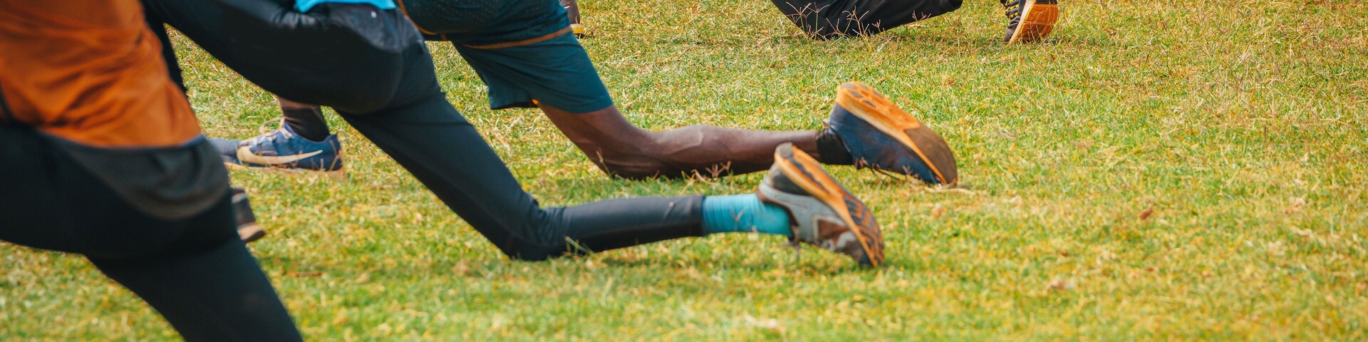 Stretching and warm-up of African runners. Joggers and marathon runners prepare to run on green grass. Photo from training in Kenya