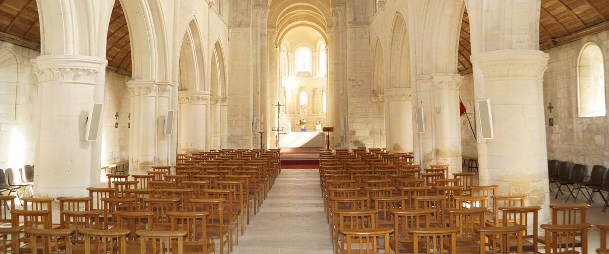 An interior of a church with rows of wooden pews, arched ceilings, and a central altar.