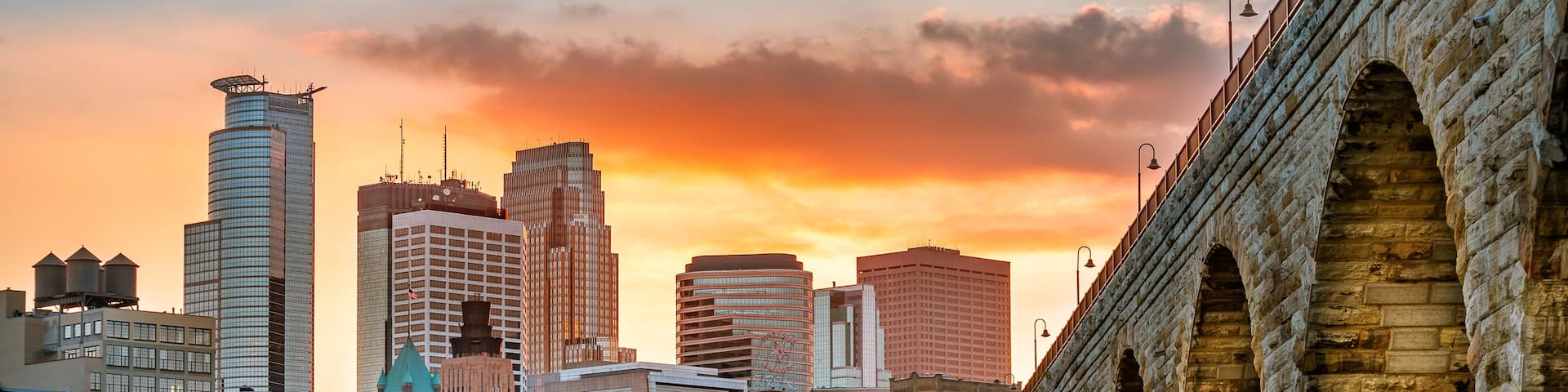 A city skyline with modern buildings and a historic stone bridge.